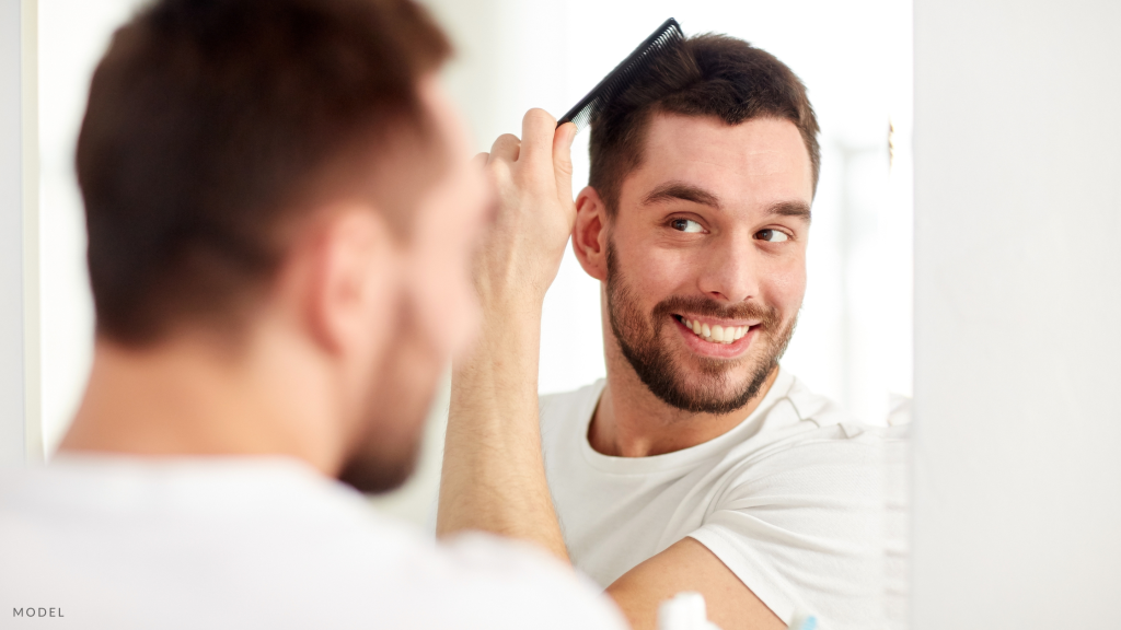 A man looking in mirror, combing his hair. (model)
